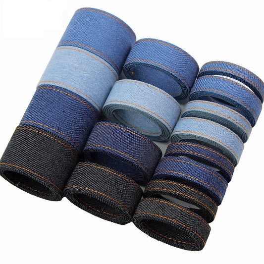 Denim fabric ribbon spool in blue tones with orange edge stitching