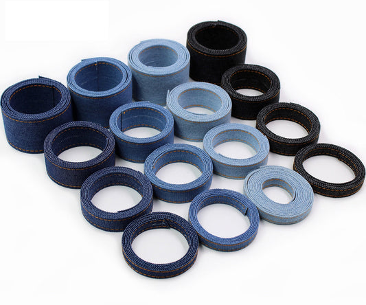 Denim fabric ribbon rolls assortment in blue and black, orange stitched edges