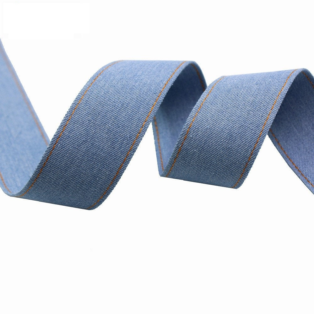 Denim fabric ribbon in blue with orange border stitching, folded roll close-up