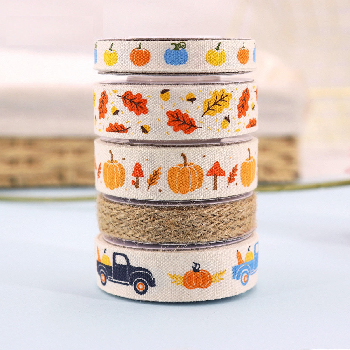 Five stacked harvest ribbon rolls: cream pumpkin and tractor designs plus burlap strip