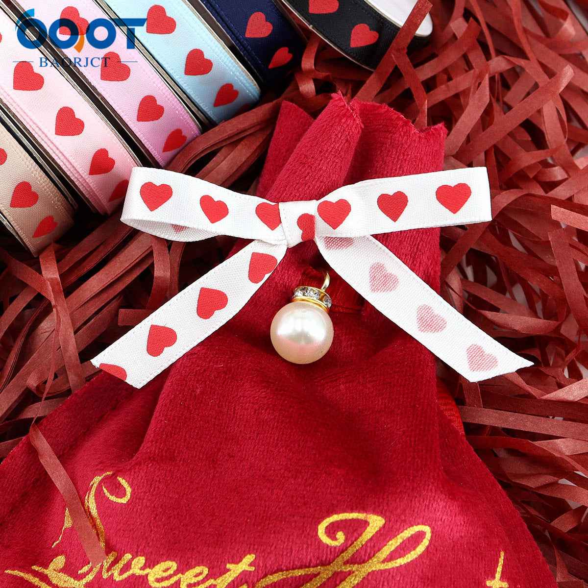 Red gift bow with white ribbon and red hearts, plus a small pearl charm