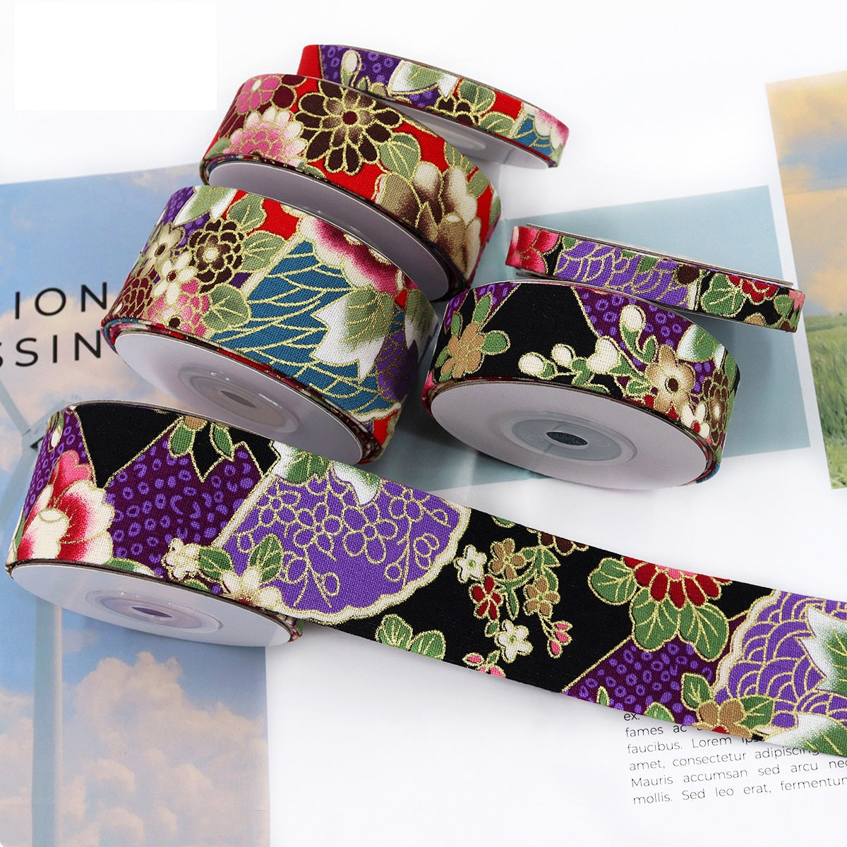 3 ribbon spools with gold-foil floral print, purple and red panels, different widths