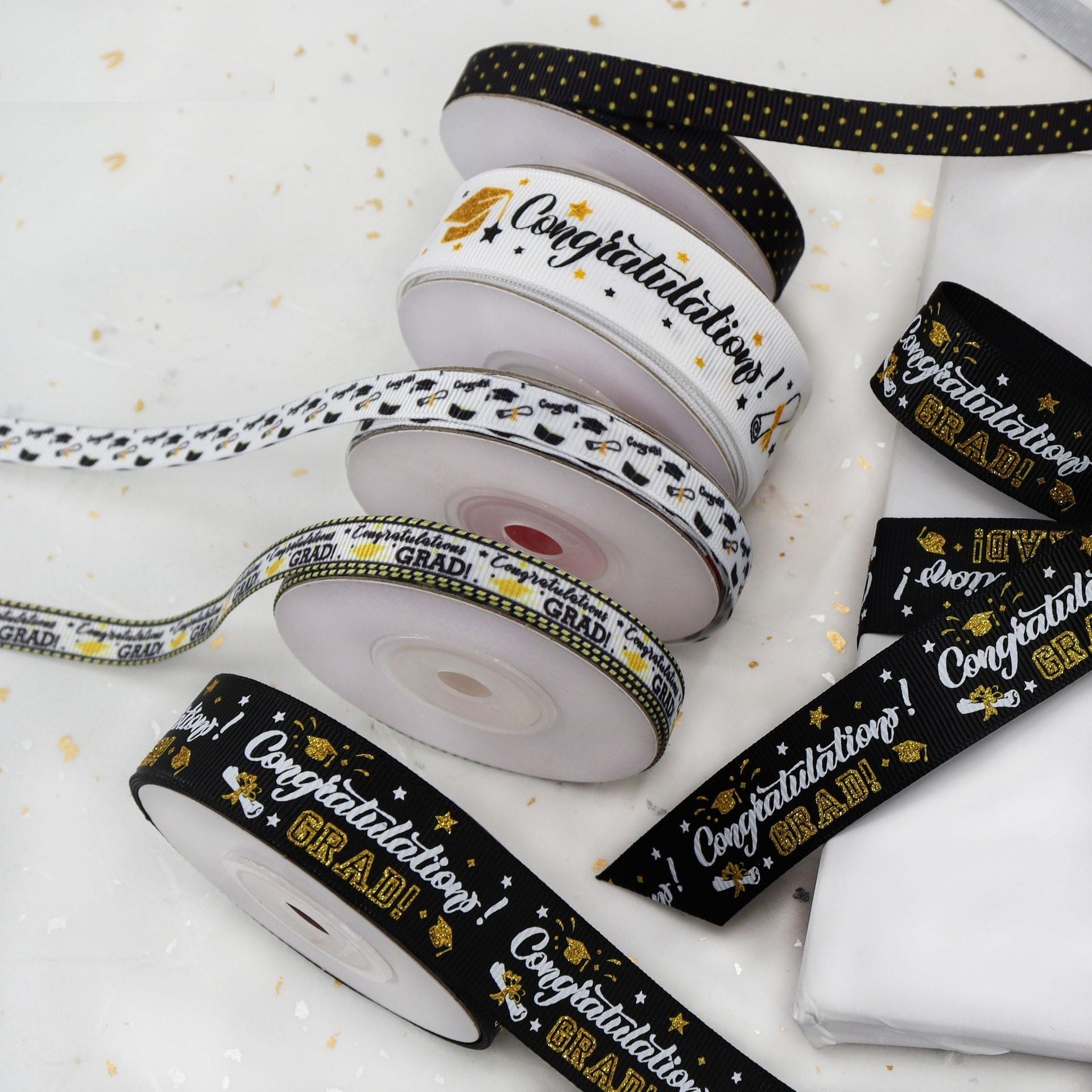 Coiled graduation ribbons: black, white, and gold “Congratulations” with “GRAD” accents