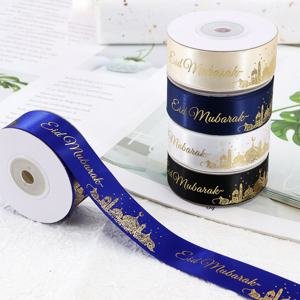 Spool of 1-inch ribbon in cream, dark blue, and black with gold Eid Mubarak text