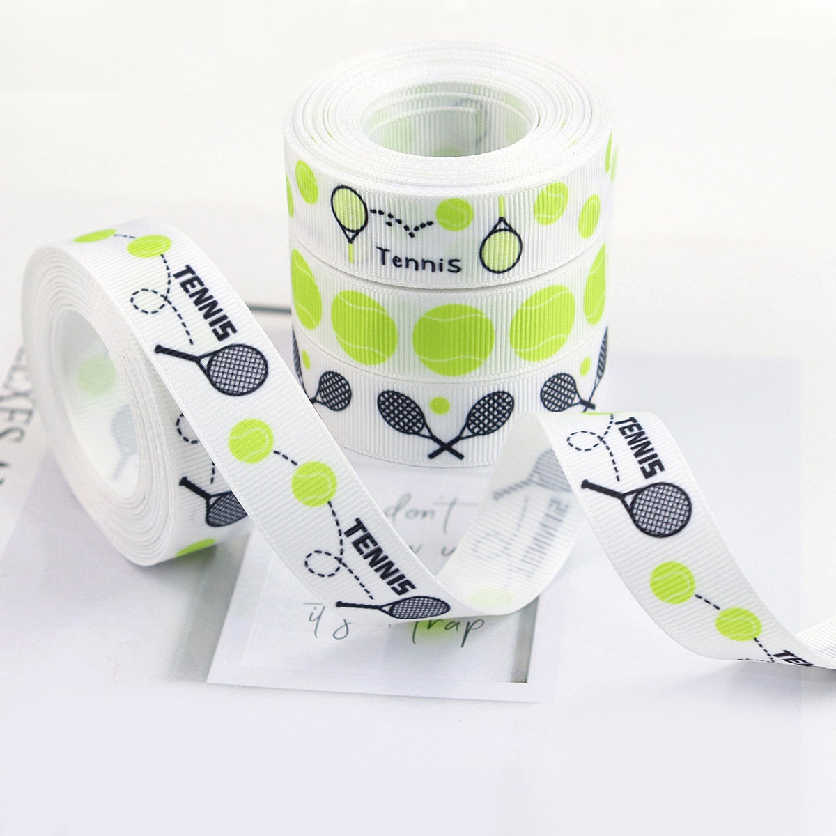 Coiled tennis grosgrain ribbon, white with green tennis balls, rackets, and “Tennis” text