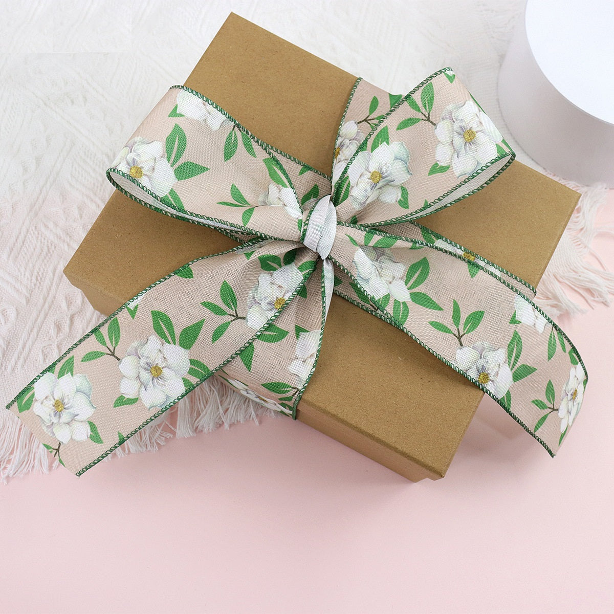 Floral wire crochet ribbon bow with fringed ends, green leaf print and white flowers
