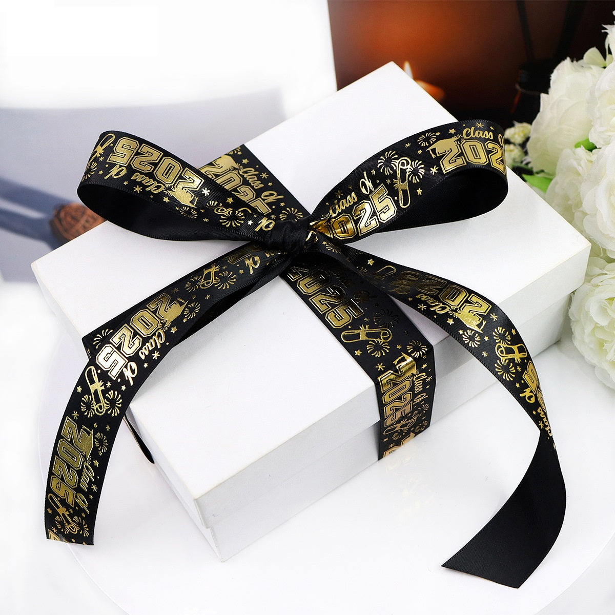 Black and gold 'Class of 2025' graduation ribbon tied in a bow on a gift box