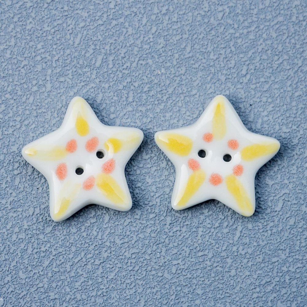 White ceramic star button with yellow accents and small pink spots, two holes
