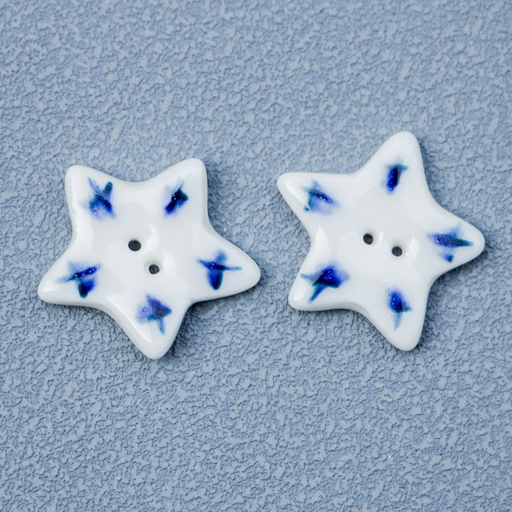 White ceramic star button with blue starburst pattern, two holes