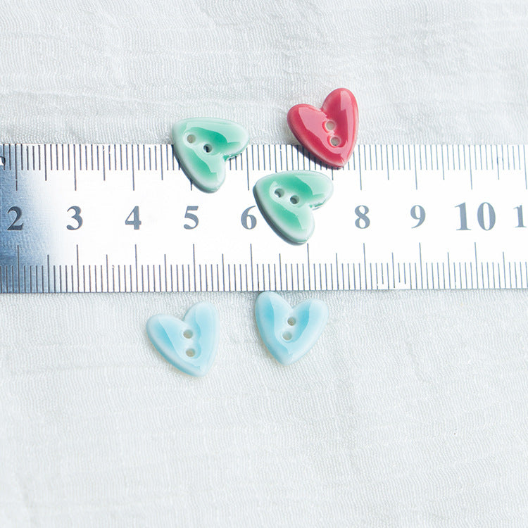 Heart-shaped 2-hole ceramic buttons on a ruler: light green, pink, and light blue
