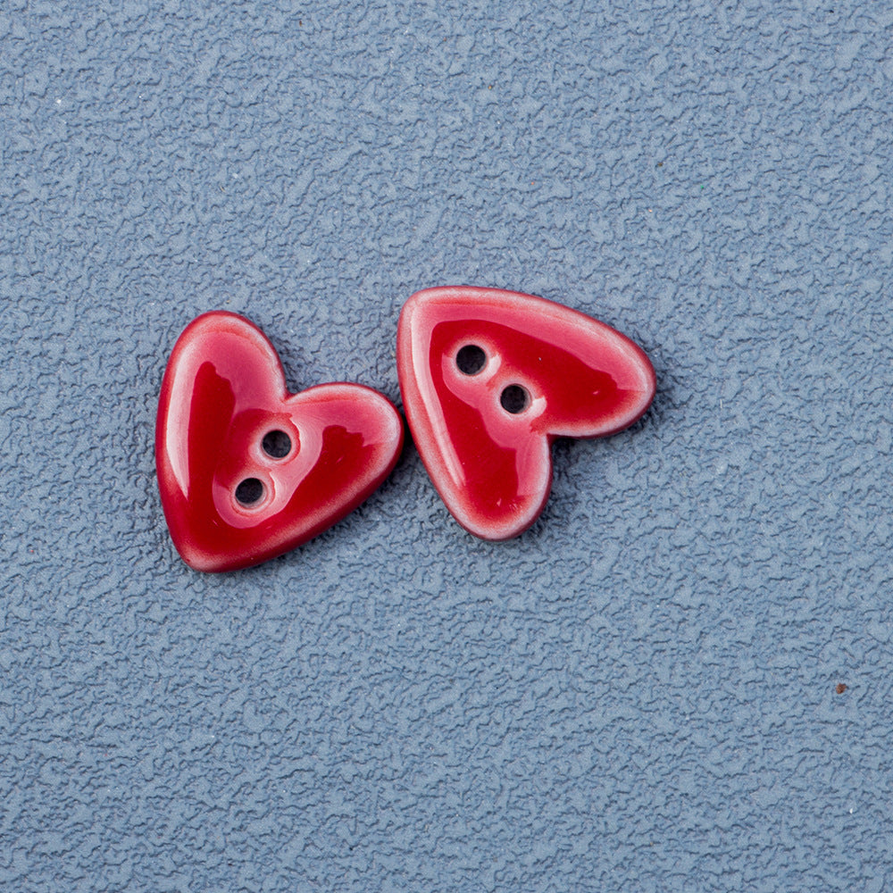 Red heart-shaped 2-hole ceramic button pair with two holes and glossy finish