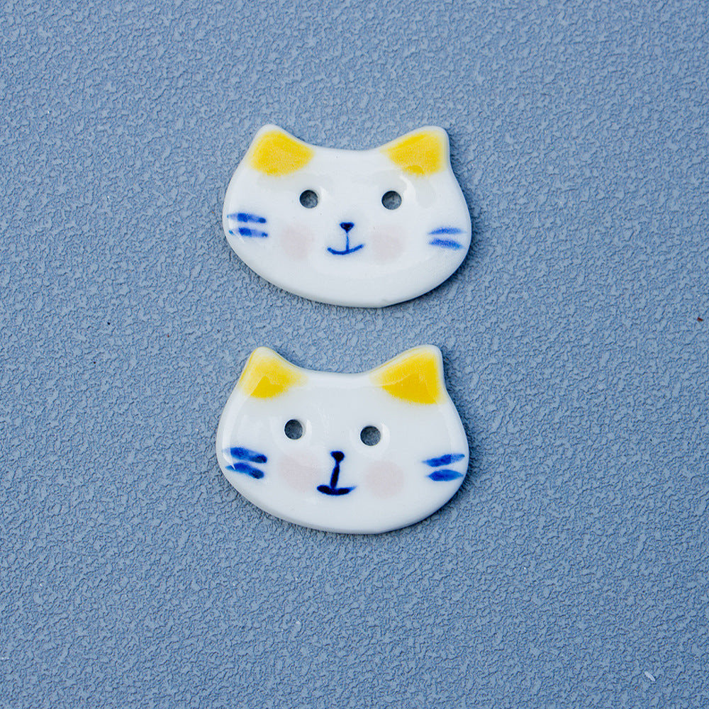 Two yellow-eared cat ceramic buttons, white glaze with 2 holes