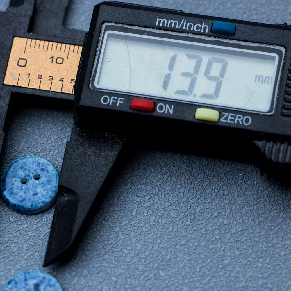 Deep blue round ceramic button with two holes, shown next to a caliper
