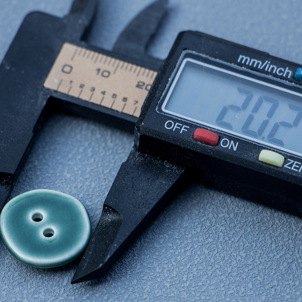 Dark green 20mm ceramic button beside digital caliper measuring 22mm
