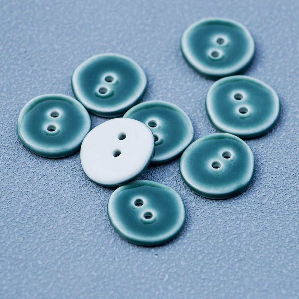 Dark green ceramic buttons with two holes; one light button among them