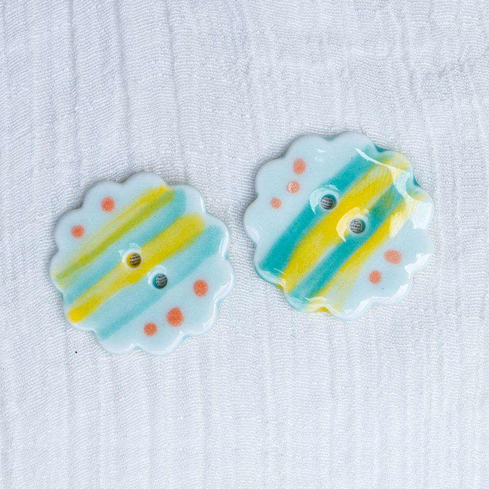 Keramikknöpfe 25 mm, 2 Löcher, blumenförmig mit gelb-blaue Streifen und orange Punkten