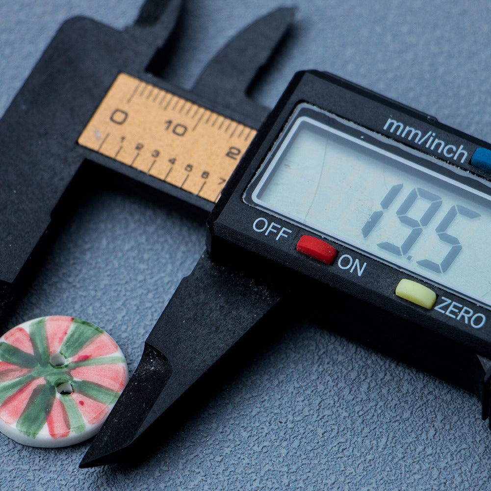 Approx. 20mm red-and-green watermelon ceramic button beside digital caliper