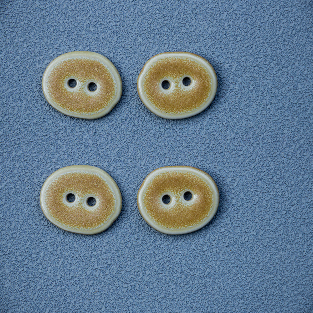 Set of sand-colored irregular oval 2-hole ceramic buttons arranged
