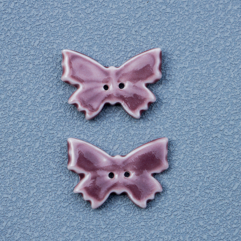 Vintage butterfly ceramic button in purple-red, 2 holes; two pieces shown.