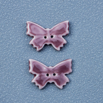 Vintage butterfly ceramic button in purple-red, 2 holes; two pieces shown.