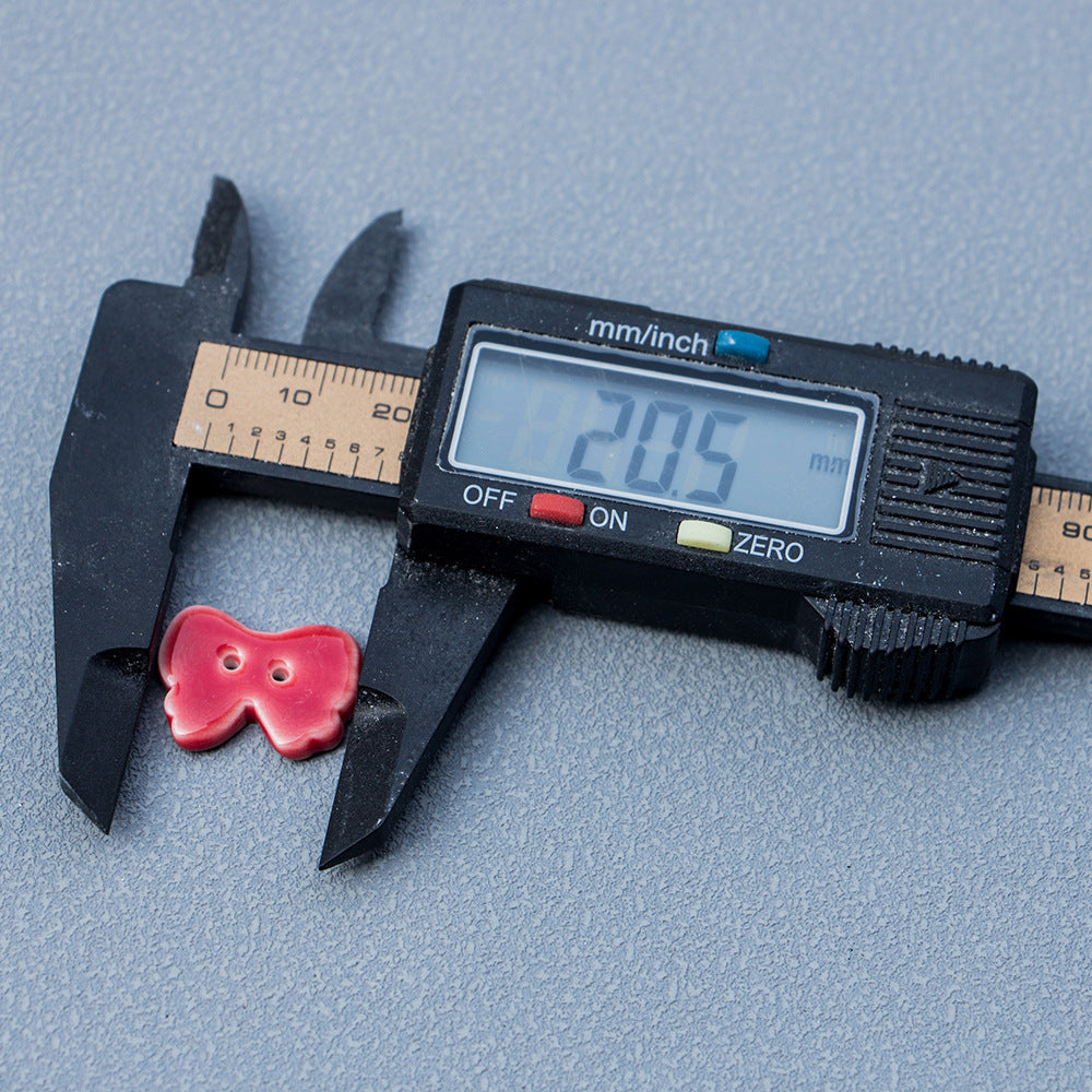 Rotfarbene 2-Loch Keramik-Bow-Button, ca. 20,5 mm, neben Messschieber