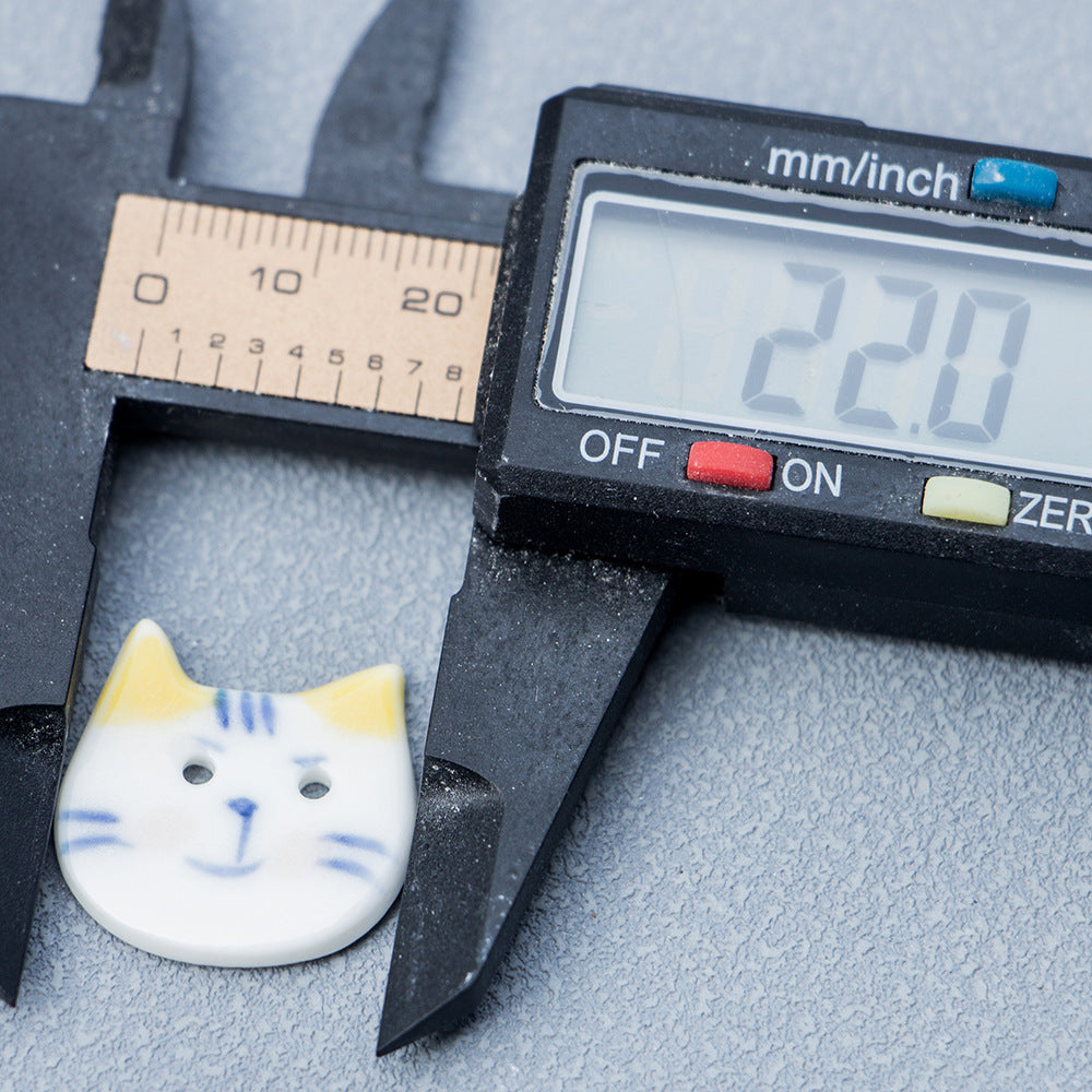 22 mm blue and white cat ceramic button with yellow ears, measured by caliper