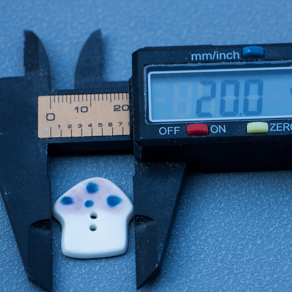 20mm mushroom ceramic button with blue dot speckles, two holes; size shown 20mm