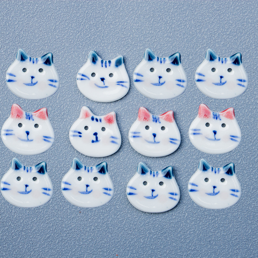 Multiple cat ceramic buttons scattered, blue ears and blue whiskers on white