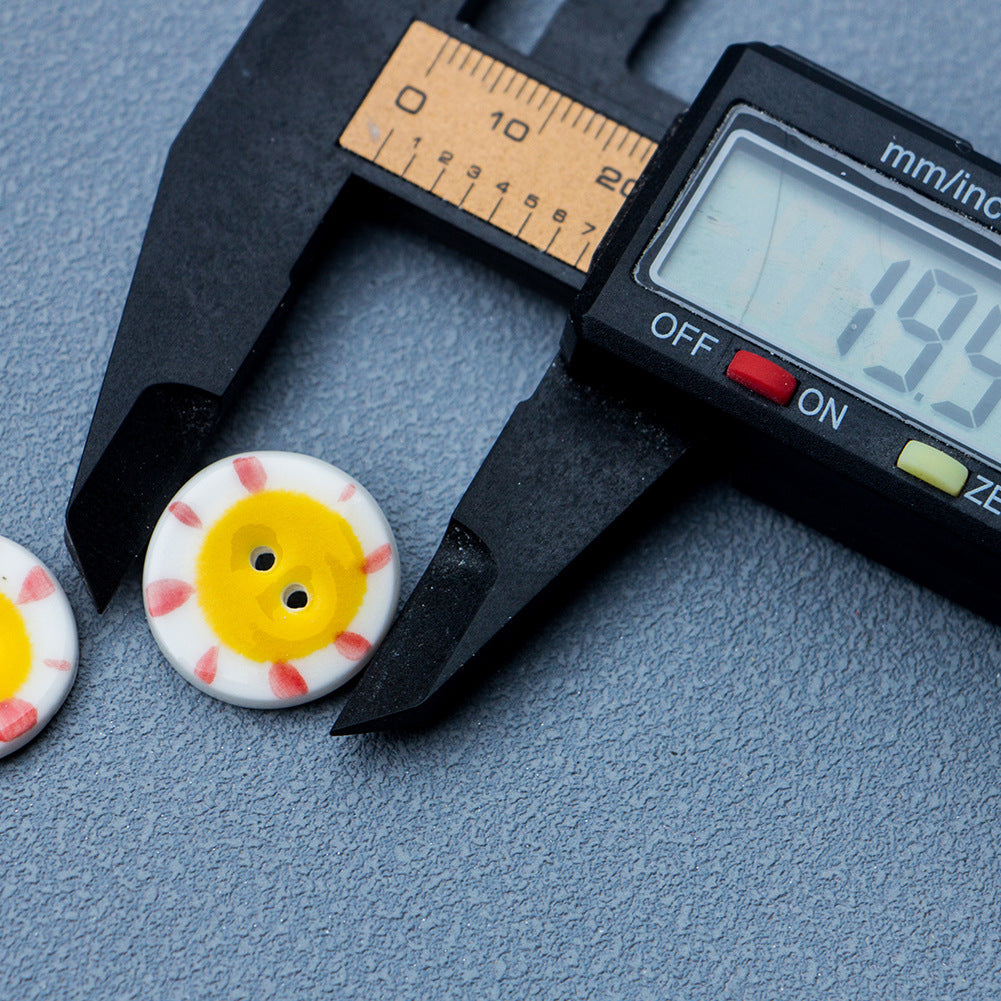 20mm round ceramic button, two holes, yellow sun pattern on white (measuring view)