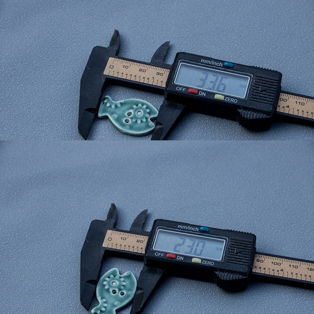Green fish-shaped ceramic 2-hole button measured with a caliper for 33 mm size.