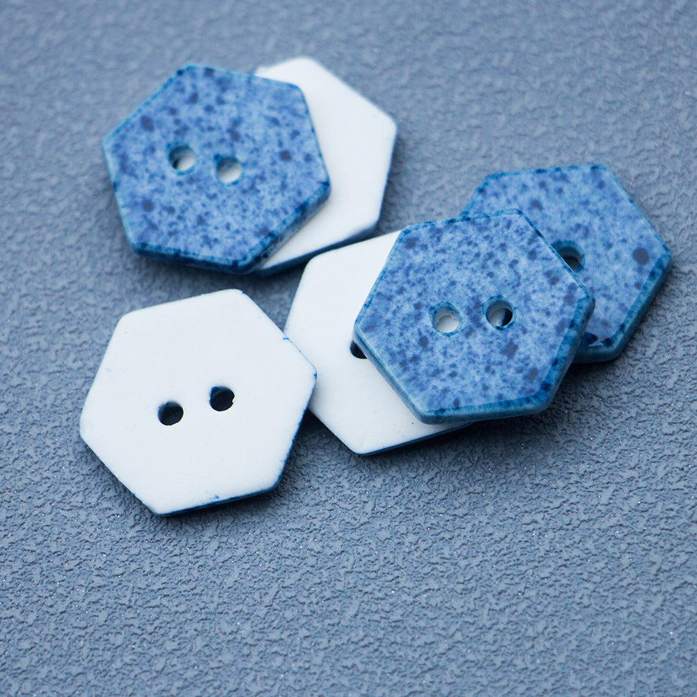 Navy blue hexagonal ceramic button with two holes, speckled texture, close-up