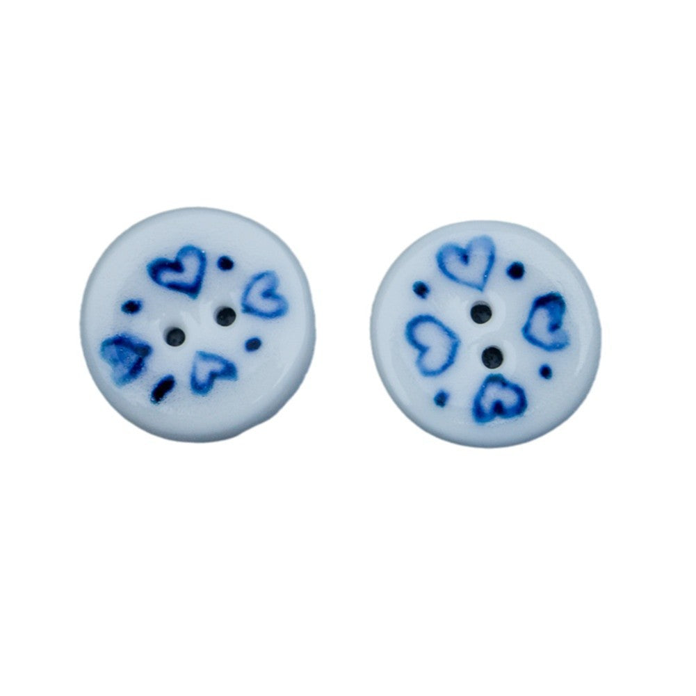 Round blue-and-white porcelain heart ceramic button, small black shank holes visible