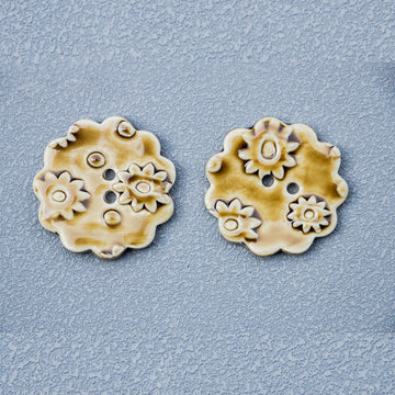 Tawny ceramic round buttons with floral relief and two holes, two shown