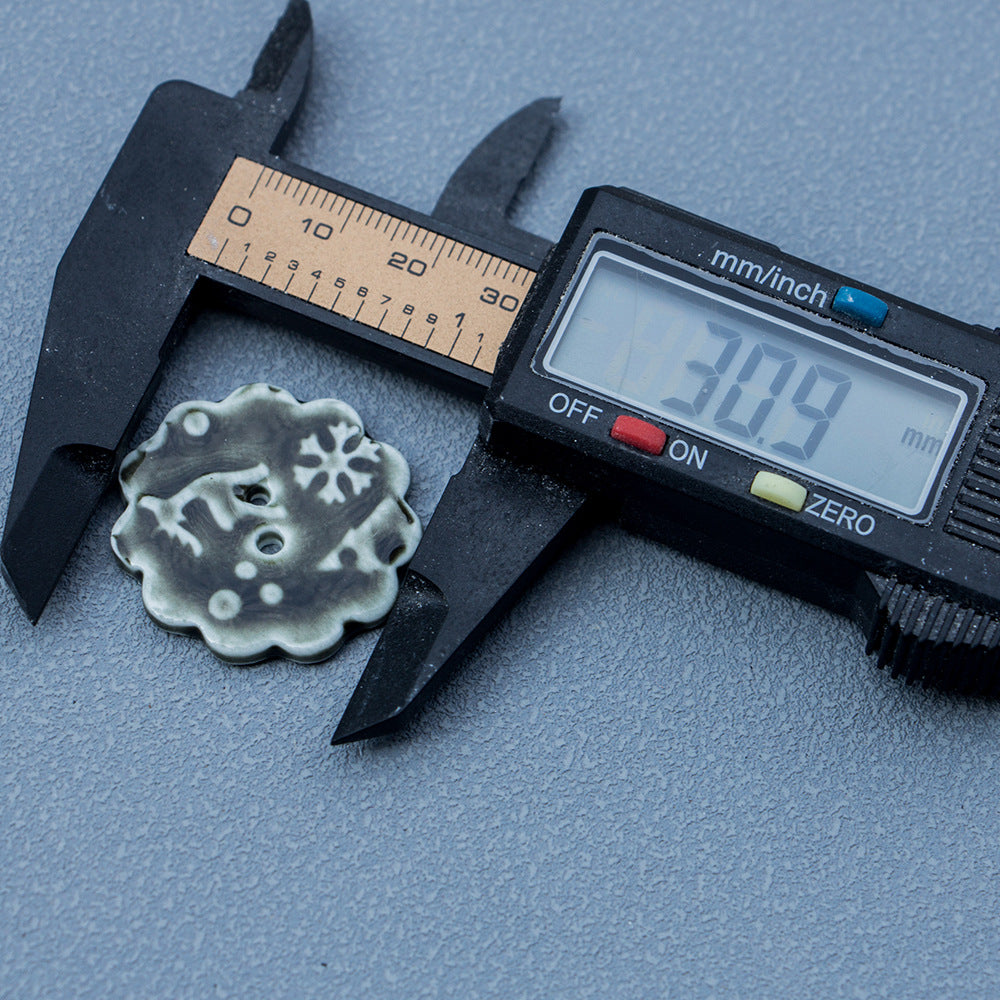 Measured ceramic 2-hole button with snowflake elk motif; caliper shows size