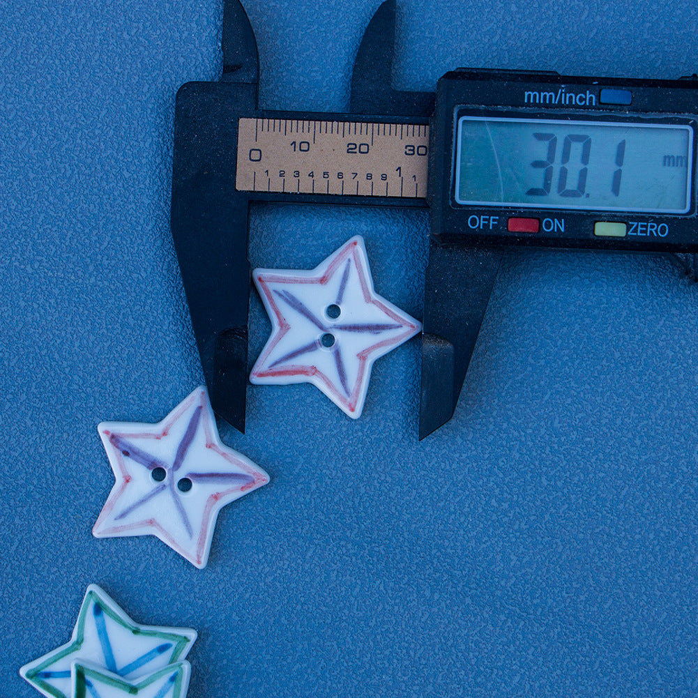 Star ceramic button, white with red/purple matchstick pattern and two holes