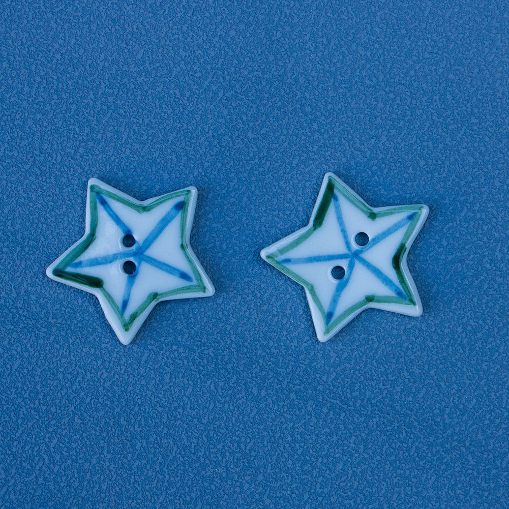 Two star ceramic buttons, white with blue-green matchstick border, two holes