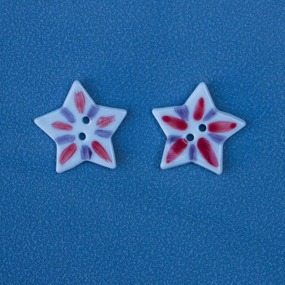 Two star-shaped ceramic buttons, white with red matchstick petals and two holes