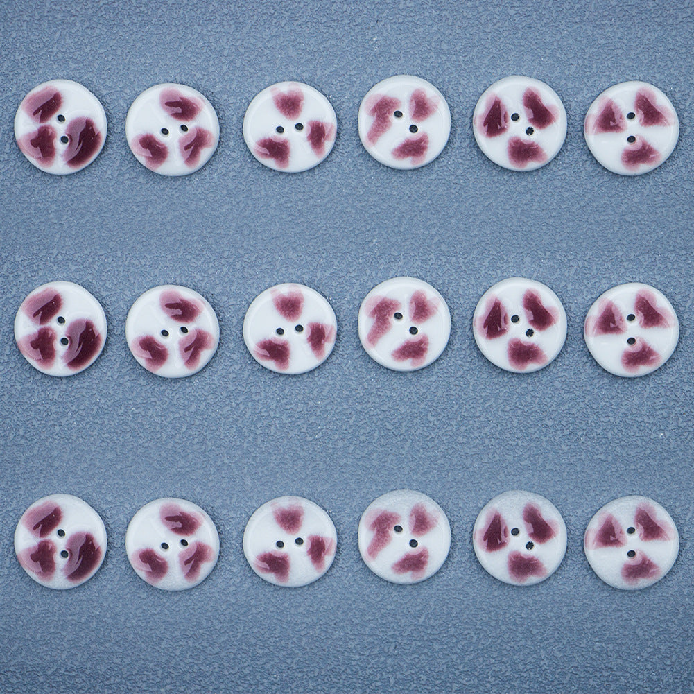 Rows of round two-hole ceramic buttons with purple heart pattern on white