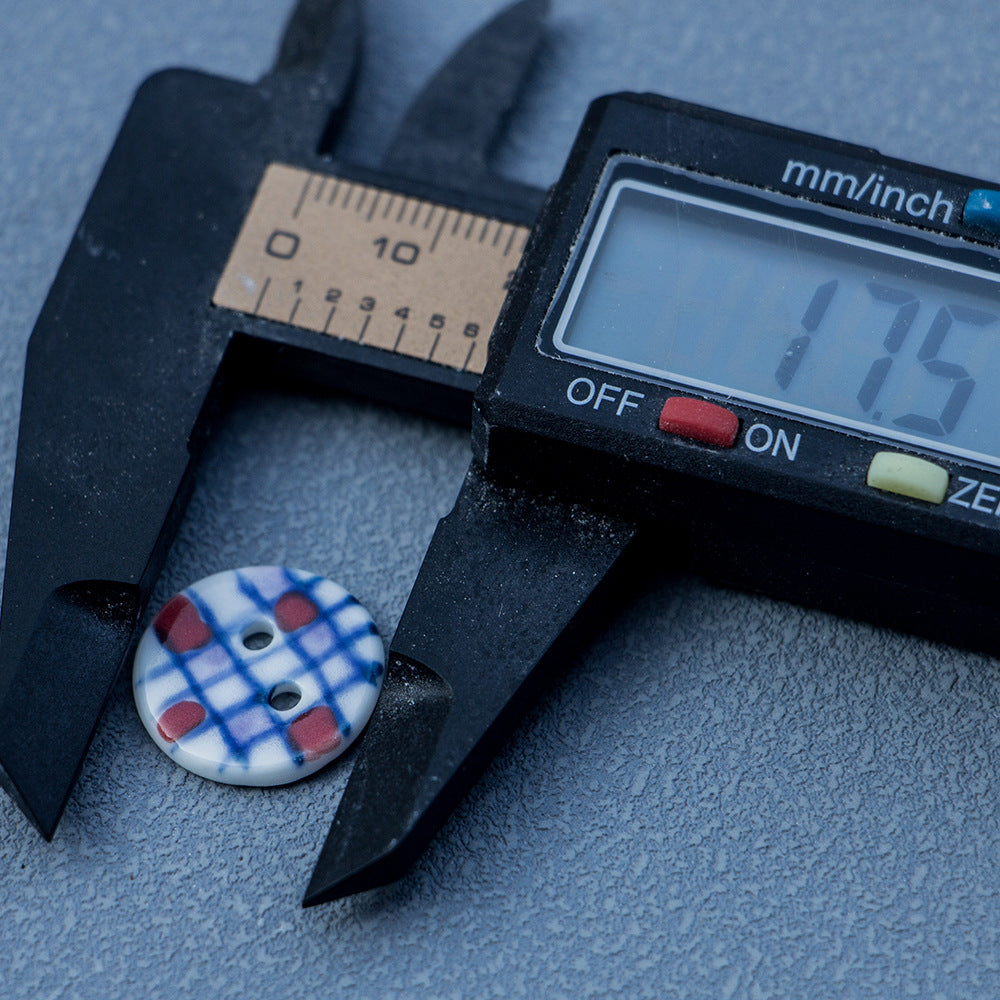 17.5mm round ceramic 2-hole blue plaid button with red accents, measured with caliper