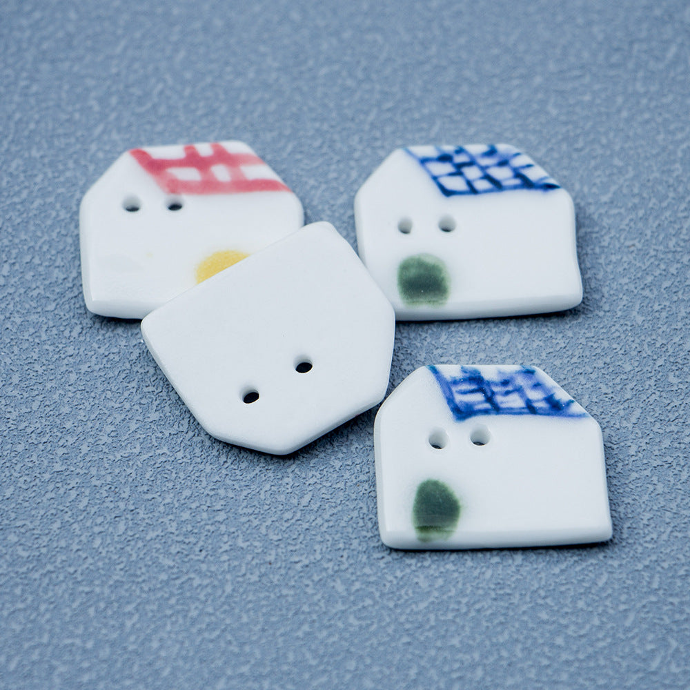 Ceramic house button pair, red/blue tiled roofs, two holes, yellow and green dots