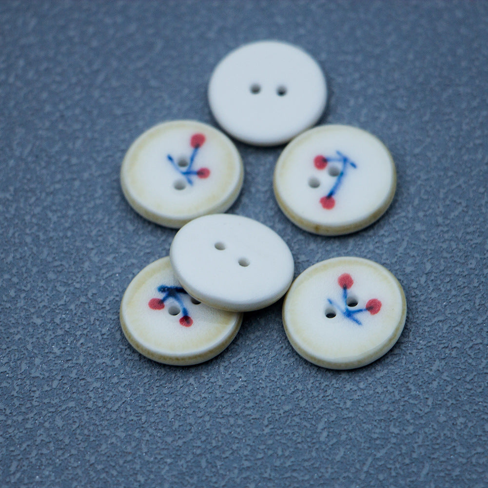Ceramic buttons: four cream cherry-pattern buttons plus one plain white button, both with 2 holes.