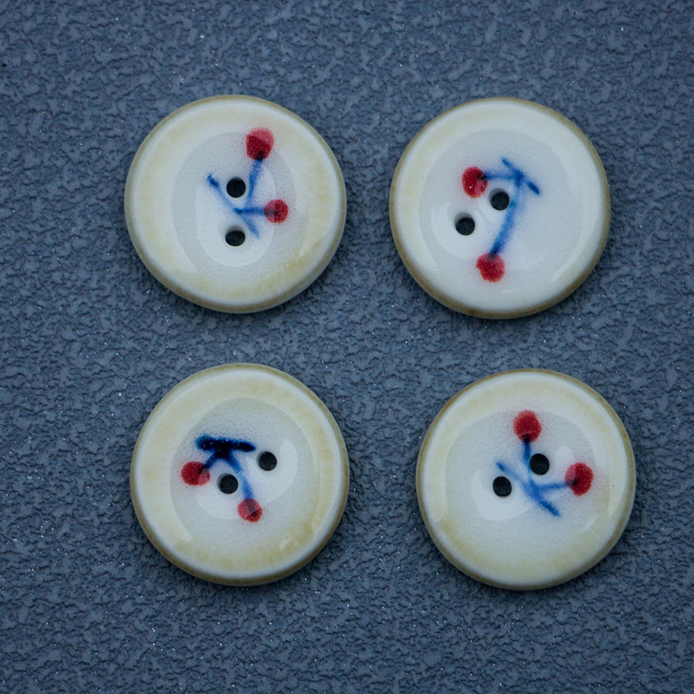 Ceramic buttons with cherry motif; cream face, blue stems, red berries, brown rim, 2 holes.