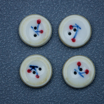 Ceramic buttons with cherry motif; cream face, blue stems, red berries, brown rim, 2 holes.