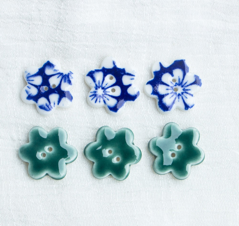 Set of small ceramic flower buttons in blue and green, each with two holes