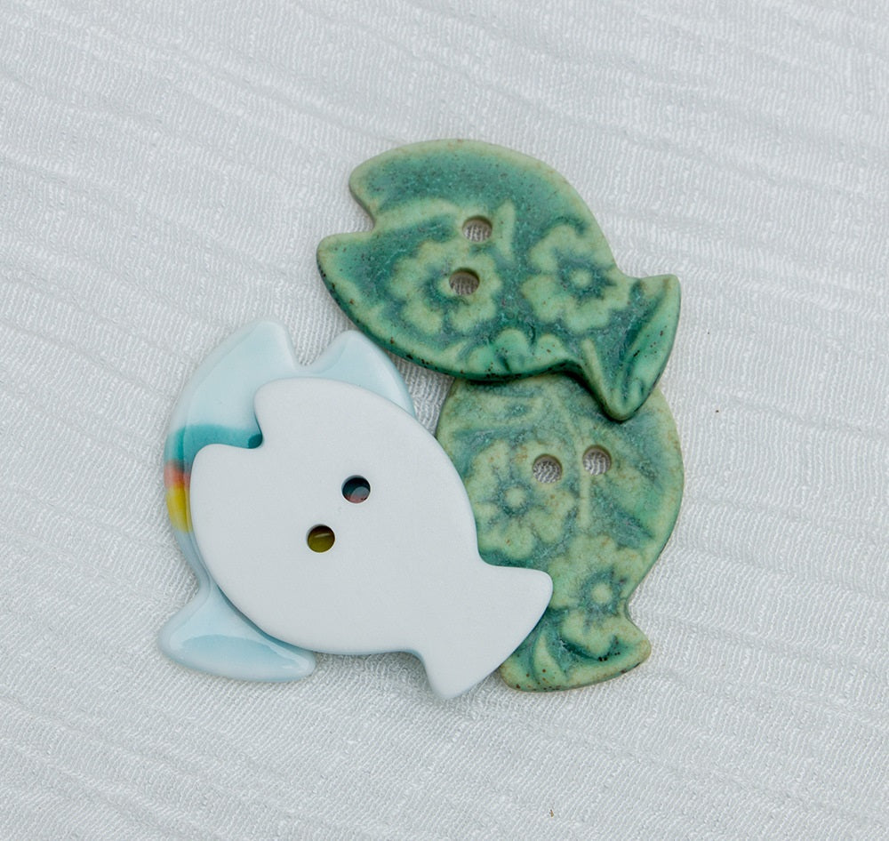 Hand-painted ceramic fish buttons with two holes: rainbow-striped white and bronze green