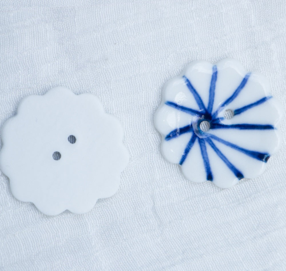 Ceramic flower buttons: one plain white with two holes, one blue-striped 30mm