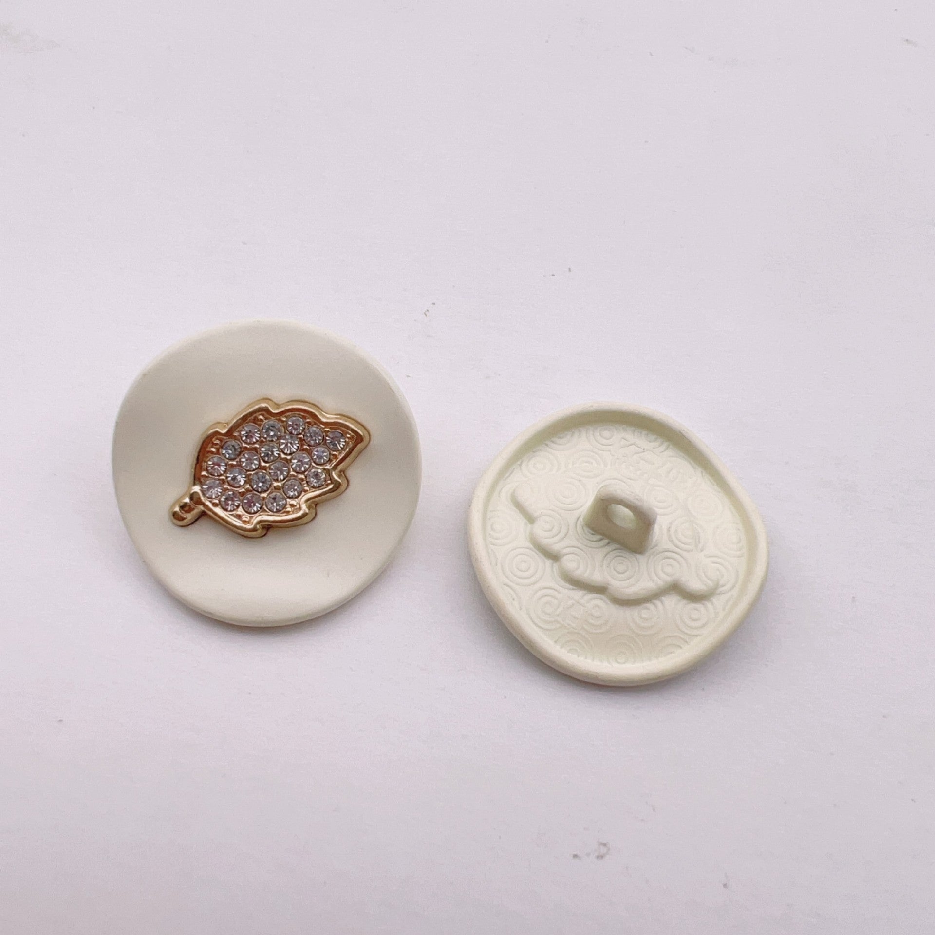 White arched jeweled button with gold leaf trim and rhinestone leaf top