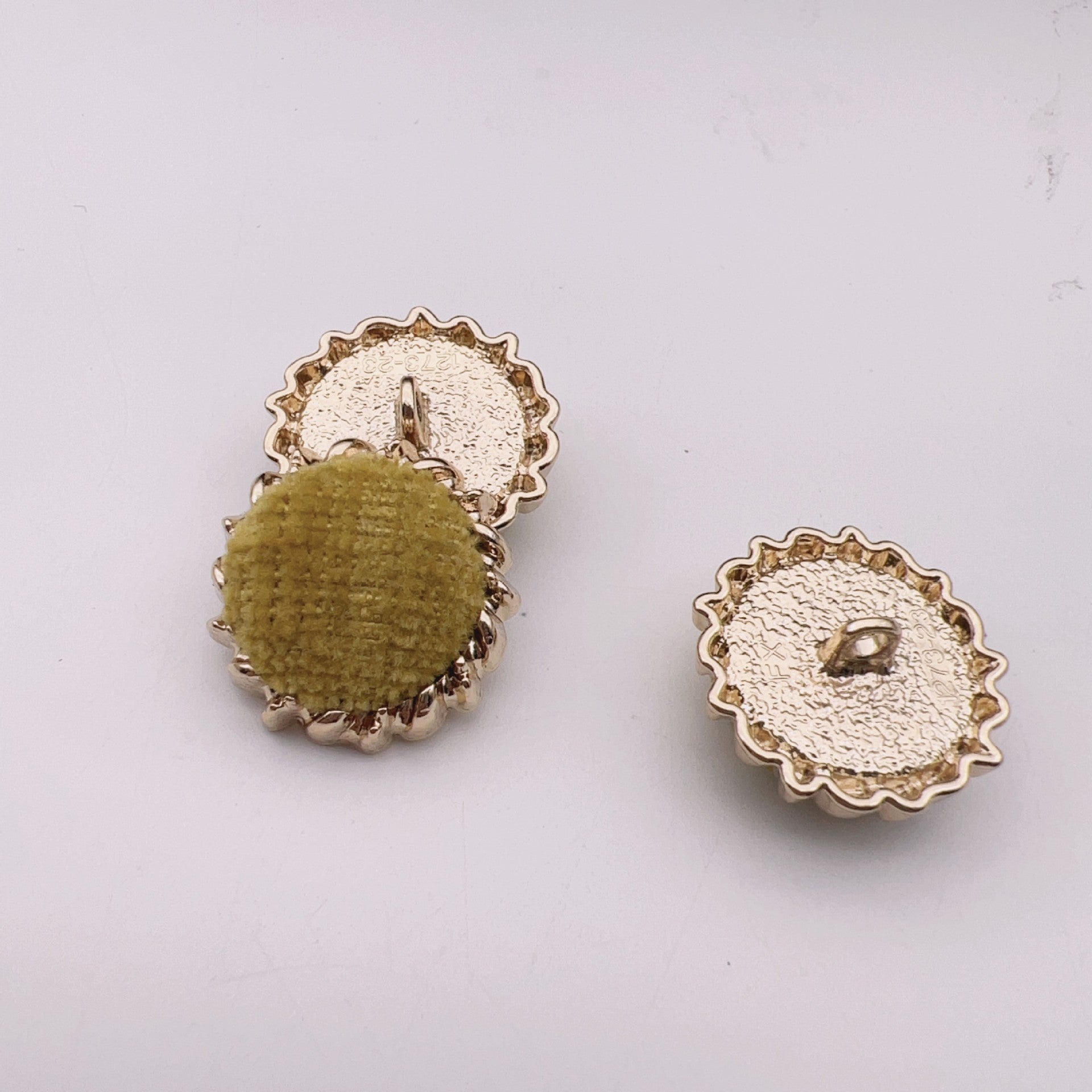 Round velvet fabric buttons, olive and white tops with gold-tone gear metal backs.