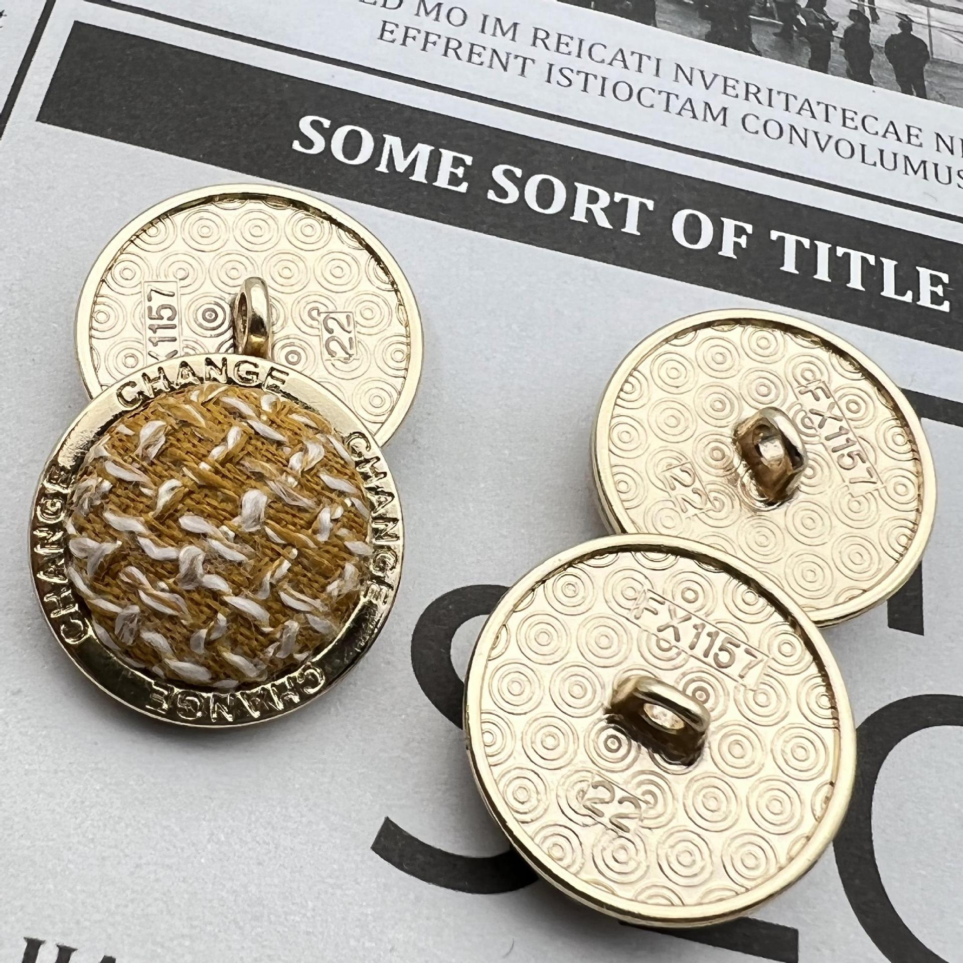 Metal edge grid shank button pair, gold rim, “CHANGE” text, tan knit-look front