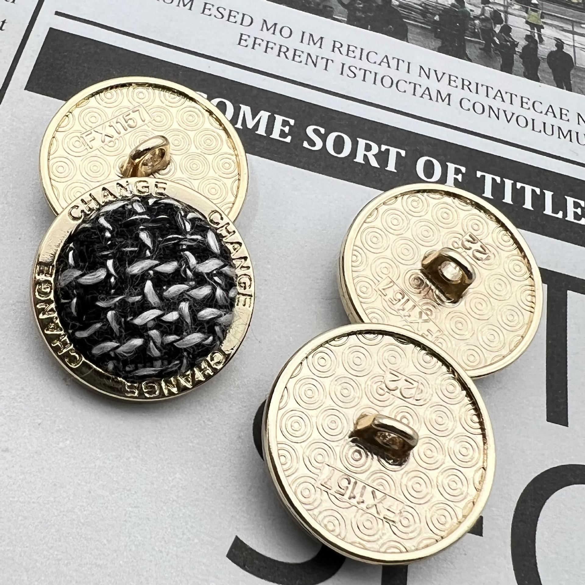 Metal shank button set on card, gold rim and “CHANGE” text, black knit-look centers